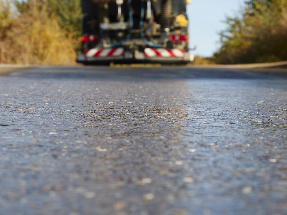 Gereinigte Asphaltstraße nach Straßenreinigung Saubere Asphaltoberfläche nach maschineller Straßenreinigung im Raum Melle mit Reinigungsfahrzeug im Hintergrund